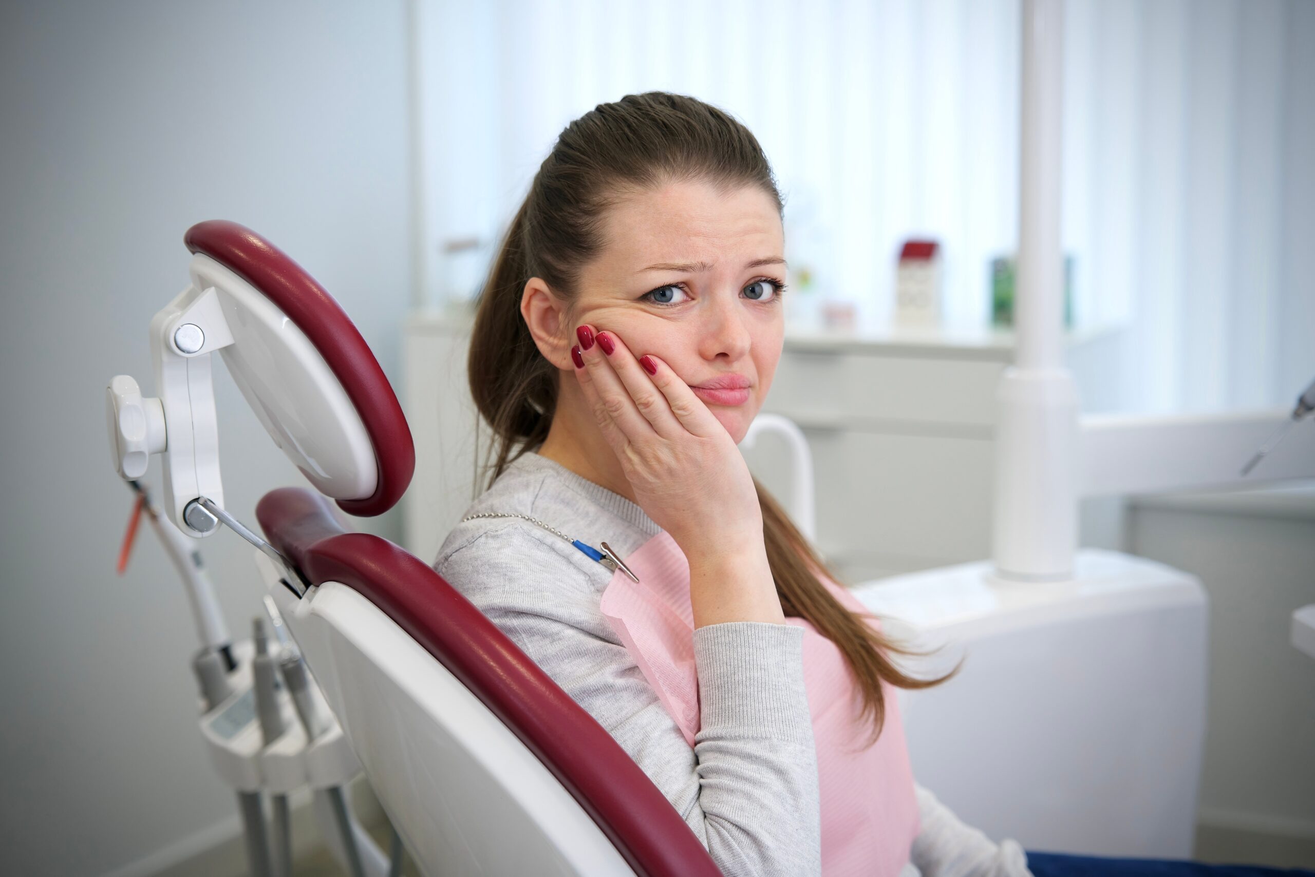 young woman suffering from tooth pain, possible need for wisdom tooth removal