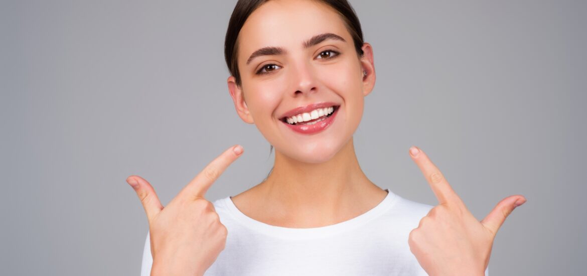 Girl showing white teeth against a gray background