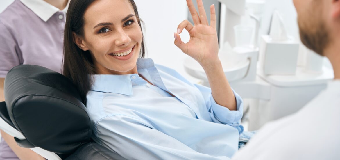 calm and positive young woman giving the Ok sign in a dental chair
