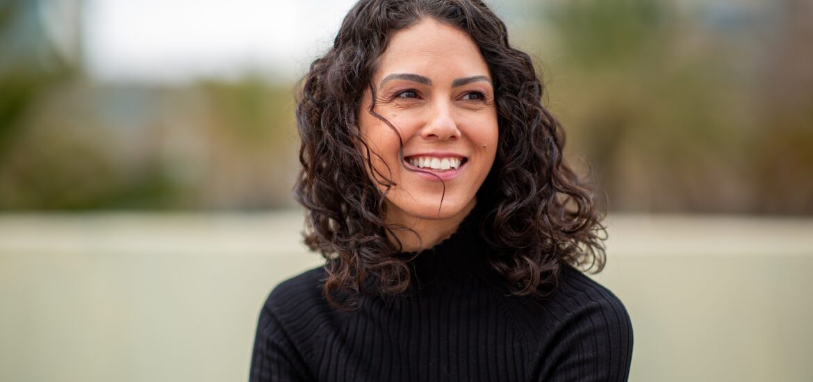 Portrait young woman smiling naturally and looking away outdoors in urban setting