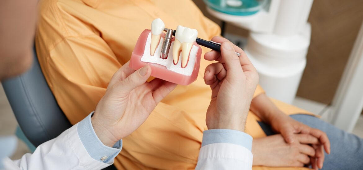 closeup of a dentist showing a patient a dental implant model